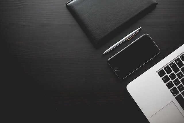 Un espace de travail moderne comprenant un ordinateur portable, un smartphone et un bloc note.