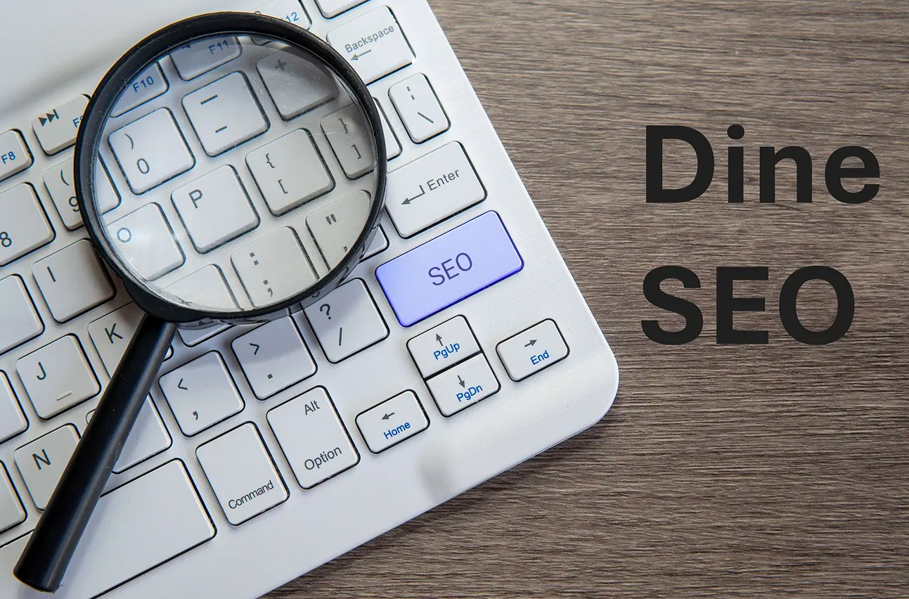 Image qui regroupe le clavier d'un ordinateur, une loupe et le manuscrit du nom de l'agence Dine SEO.